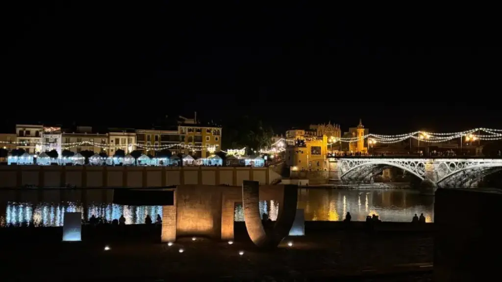 Casetas iluminadas de la Velá de Triana junto al puente de Triana, un clásico de qué hacer en Sevilla en julio