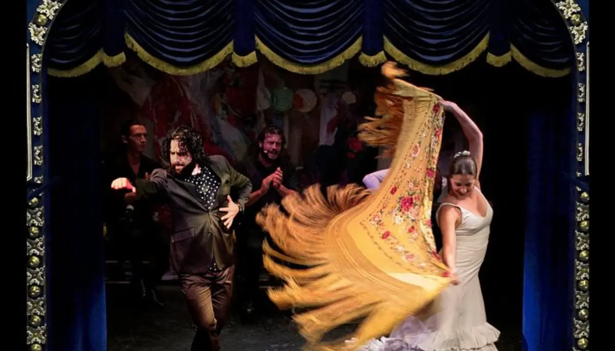 Bailaora com mantón e músicos no palco do Teatro Flamenco Triana de Sevilha