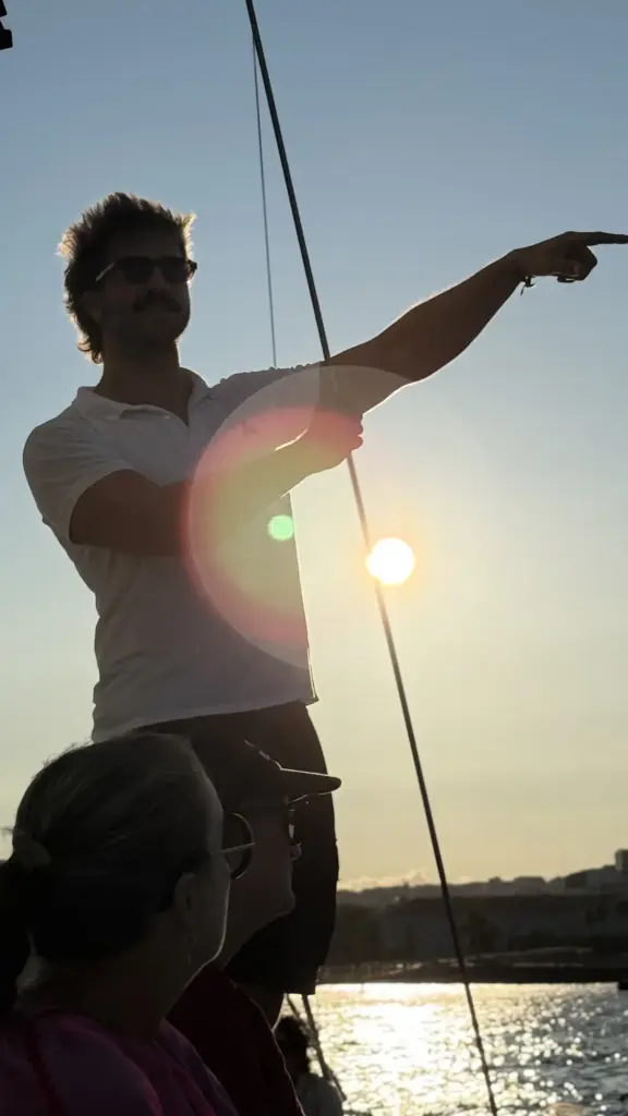 El capitán señala el atardecer desde el velero en el río Tajo
