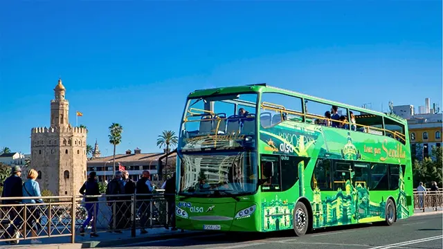 Bus turístico verde de Sevirama junto a la Torre del Oro